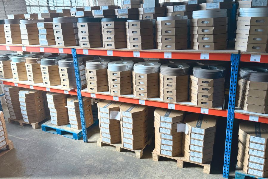 Shelves stacked with boxed edge banding rolls and sample cartons ready to ship from the warehouse