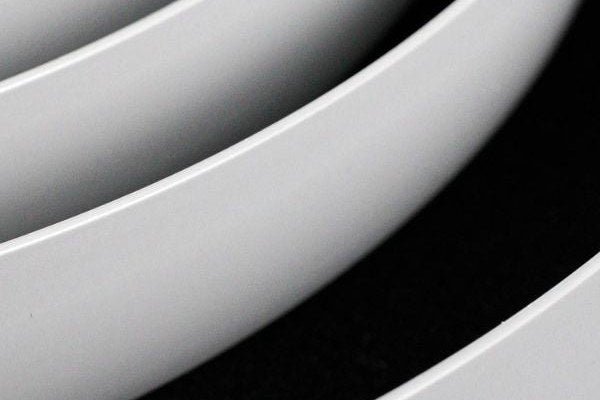 Coils of smooth white edge banding on a black background