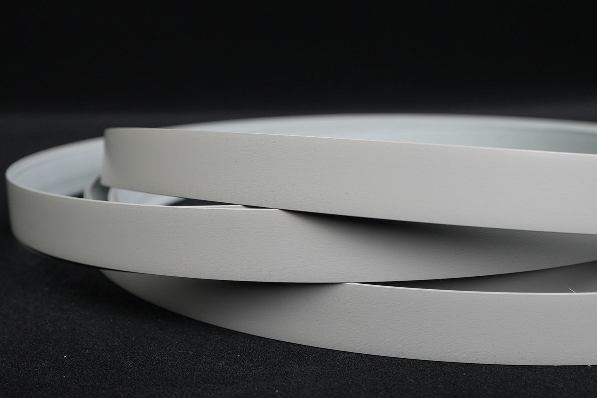 Rolls of white edge banding on a dark background